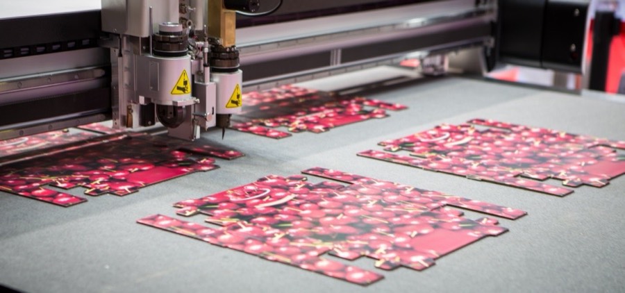 Digital knife cutter head cutting printed carton blanks with a cherry design on the flatbed