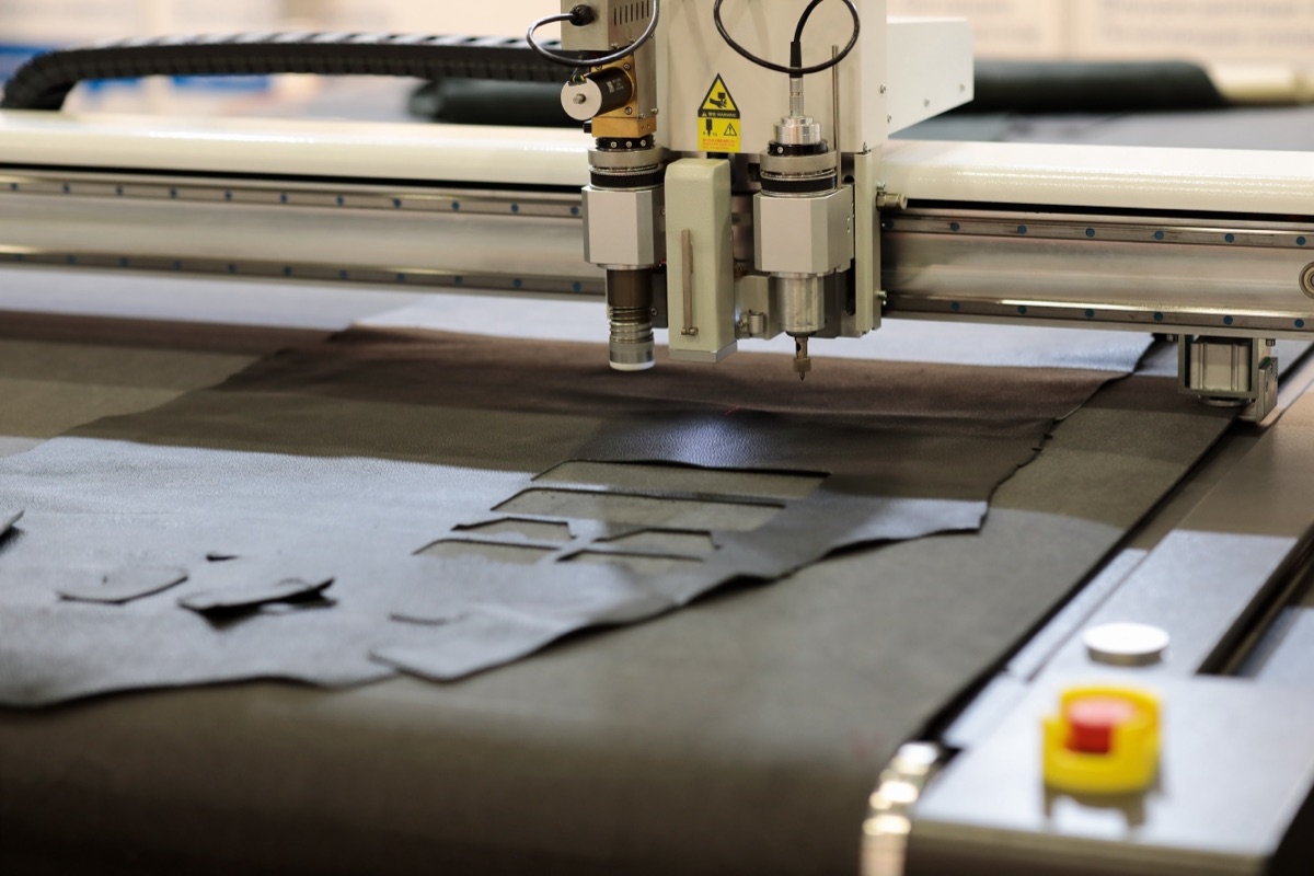 Oscillating and drag knife heads cutting small components from dark rubber sheet on the flatbed