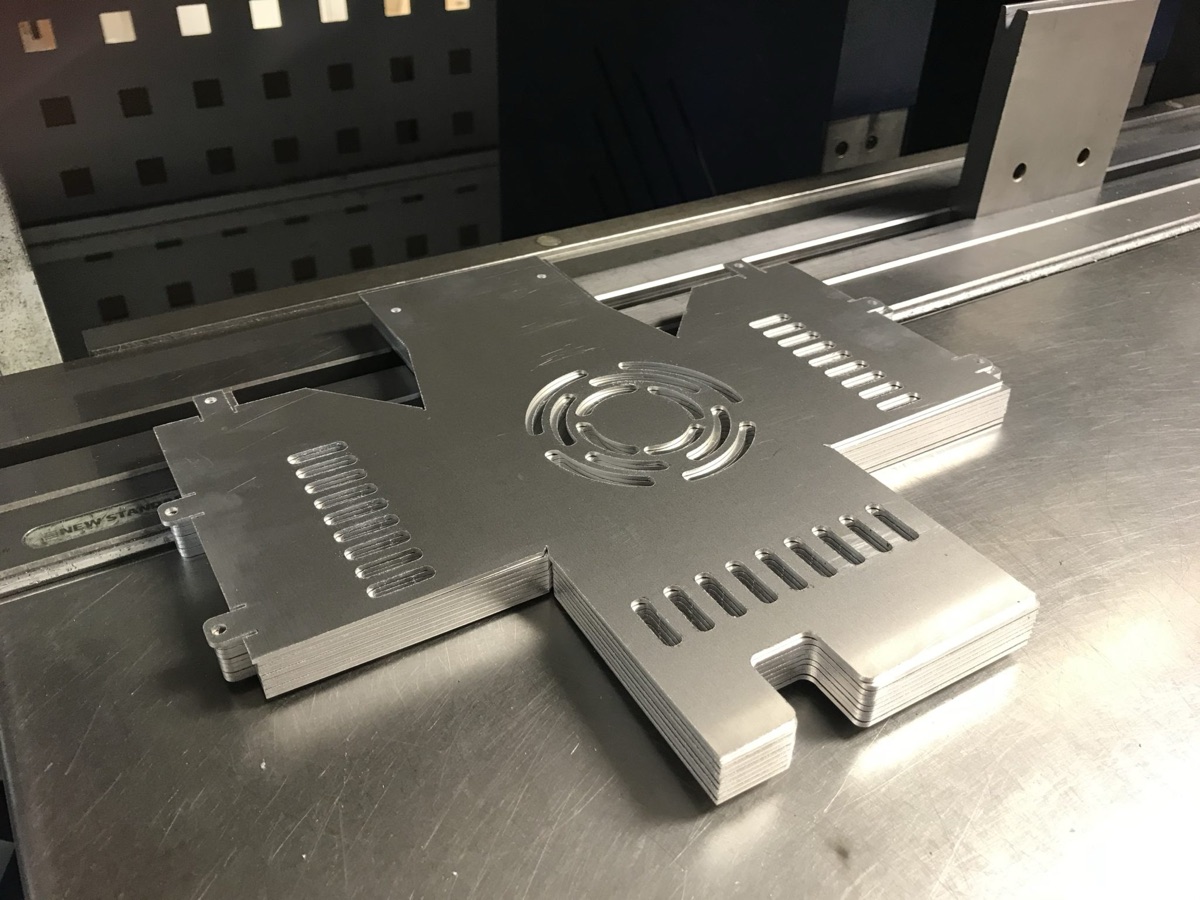 Stacked aluminium enclosure blanks with vent slots and fan aperture, cut ready for folding