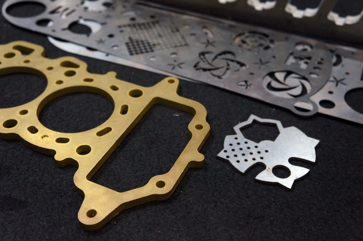 Laser-cut brass gasket-style plate and stainless decorative panels with fine internal detail