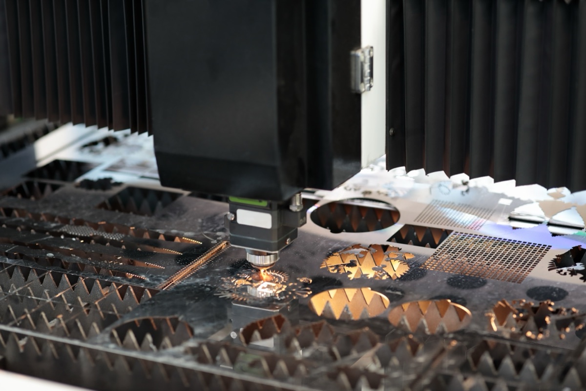 Fiber laser head cutting intricate technical profiles from stainless sheet