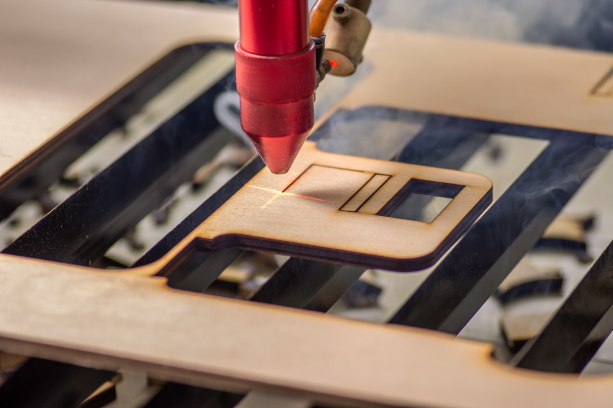CO2 laser cutting a plywood component with the beam visible on the sheet