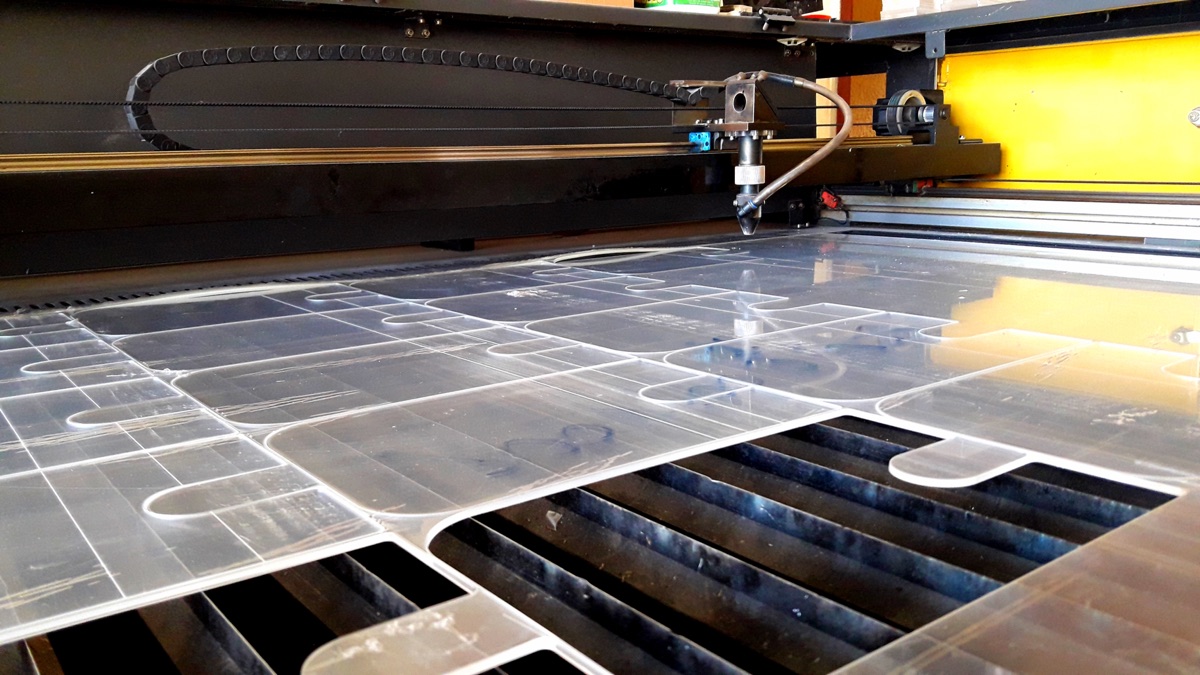 Nested clear acrylic parts cut across a full sheet on the CO2 laser bed