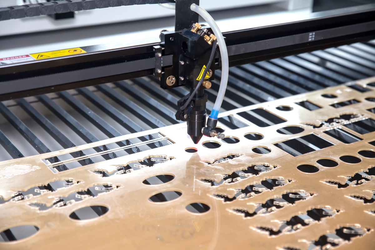 CO2 laser head cutting small parts from a bronze mirror-finish acrylic sheet
