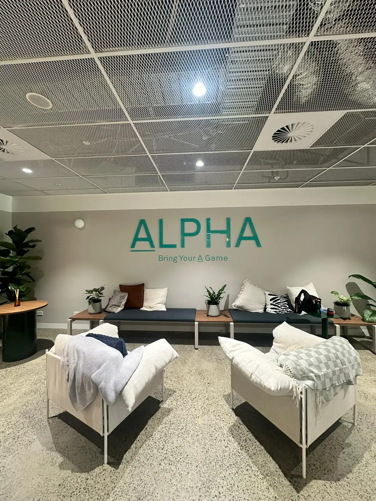 Wide view of Alpha Group's acrylic logo across a furnished Sydney CBD office lounge