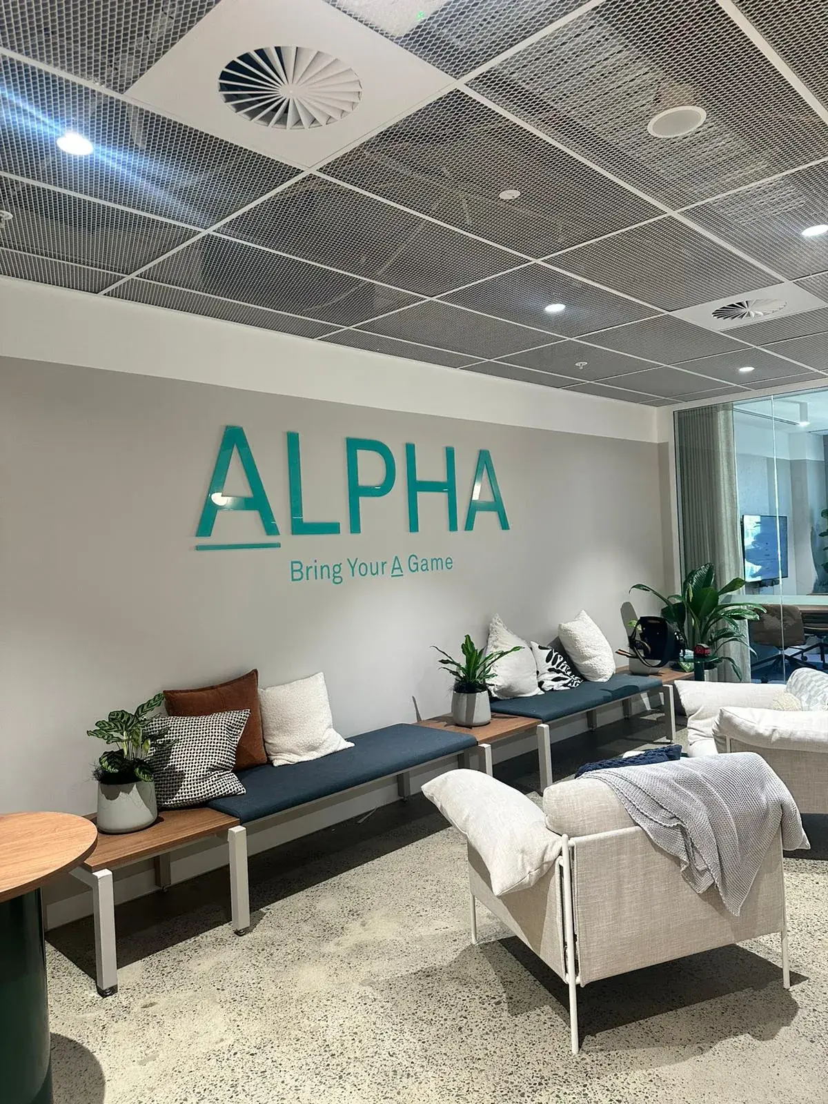 Alpha Group reverse-printed turquoise acrylic logo installed above lounge seating in its Sydney CBD office