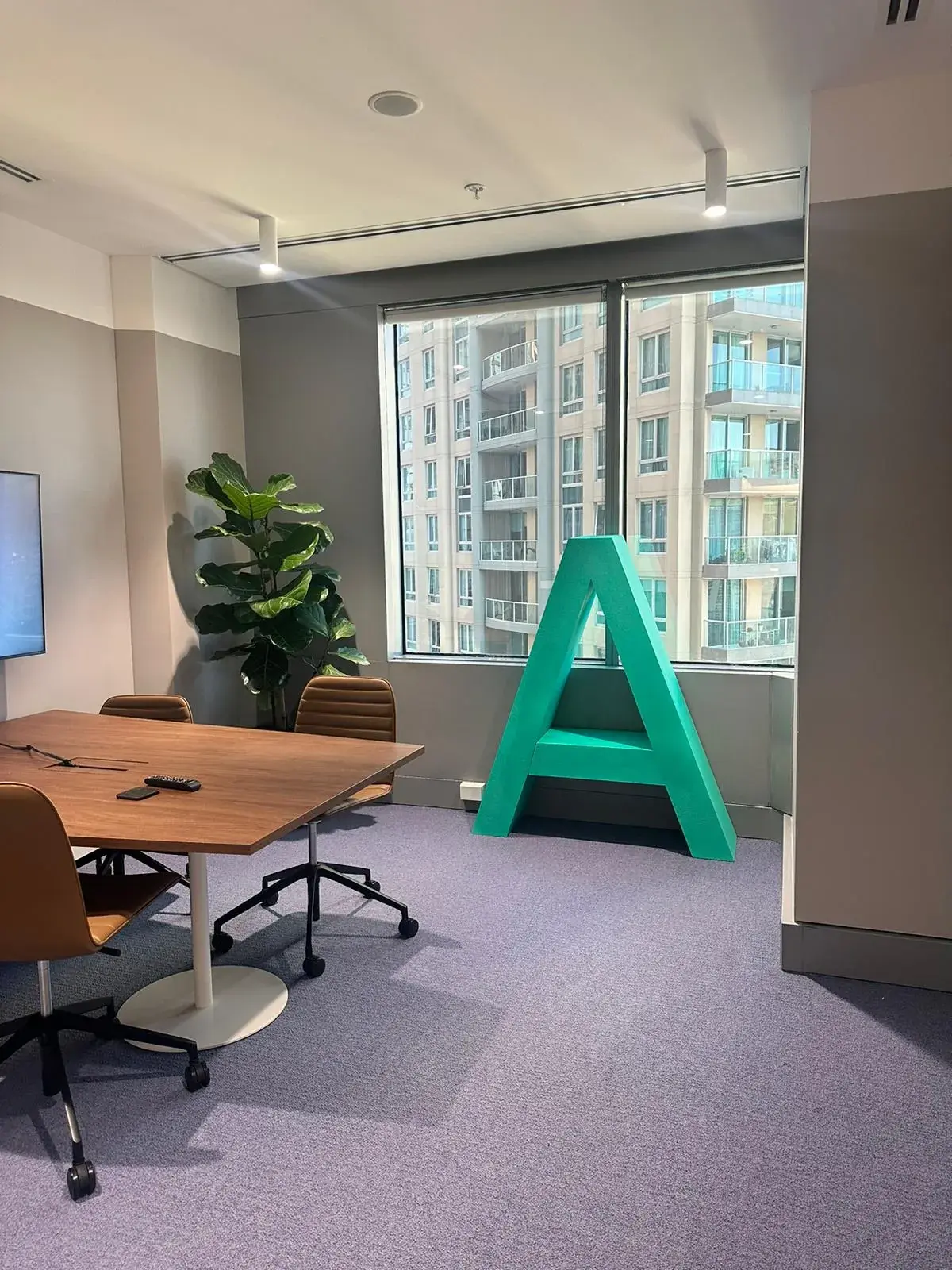 Large green painted polystyrene letter A beside a meeting table in Alpha Group's Sydney office