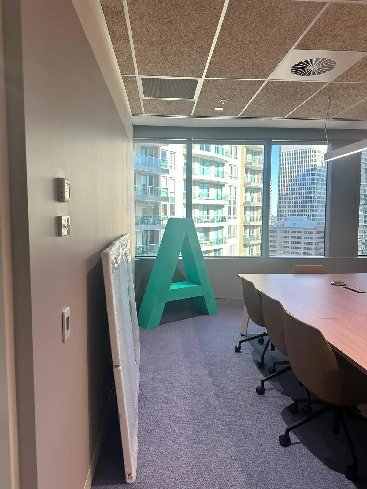 Side view of Alpha Group's freestanding green A in a high-rise meeting room