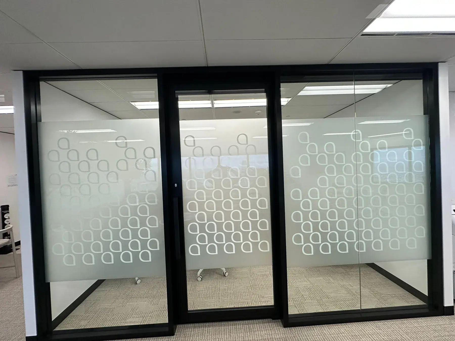 Completed three-panel Aramco meeting room with patterned frost film across the glass