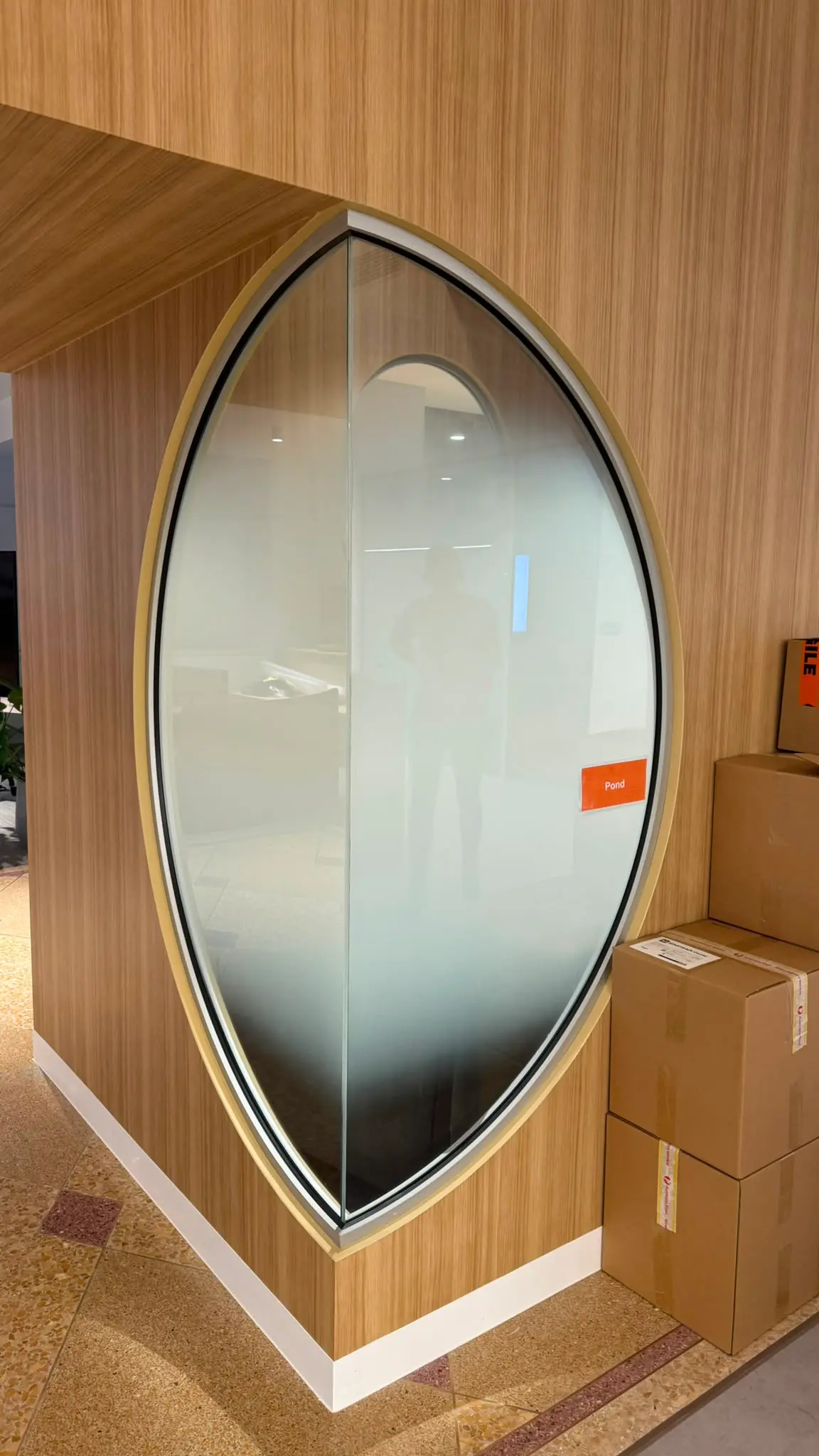 Leaf shaped curved window in a timber veneer wall with gradient film contour cut to the curve and an orange room name label reading Pond