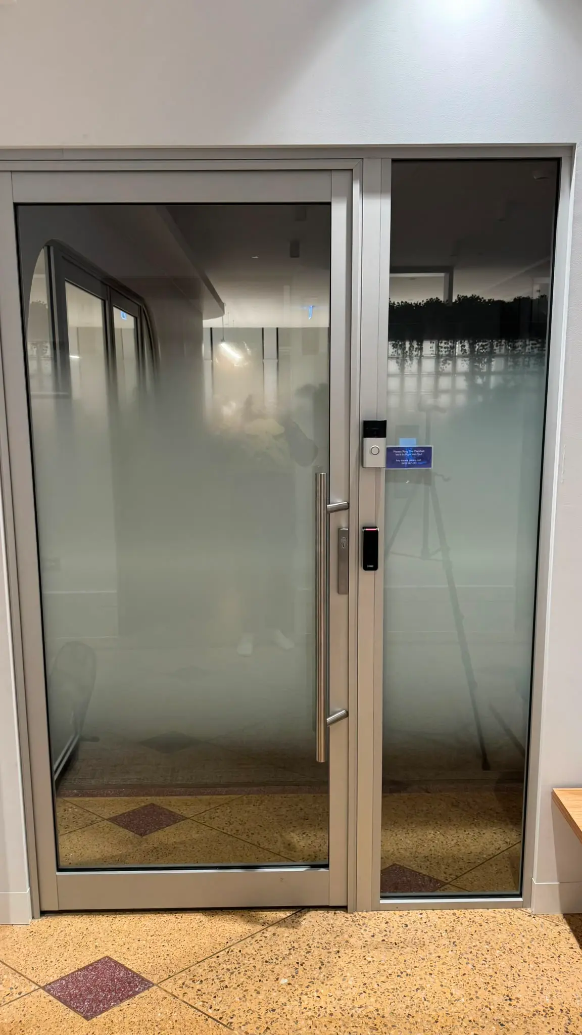 Glazed entry door and matching sidelight with the printed gradient at its densest across the base, a brushed stainless pull handle and a card reader beside the frame