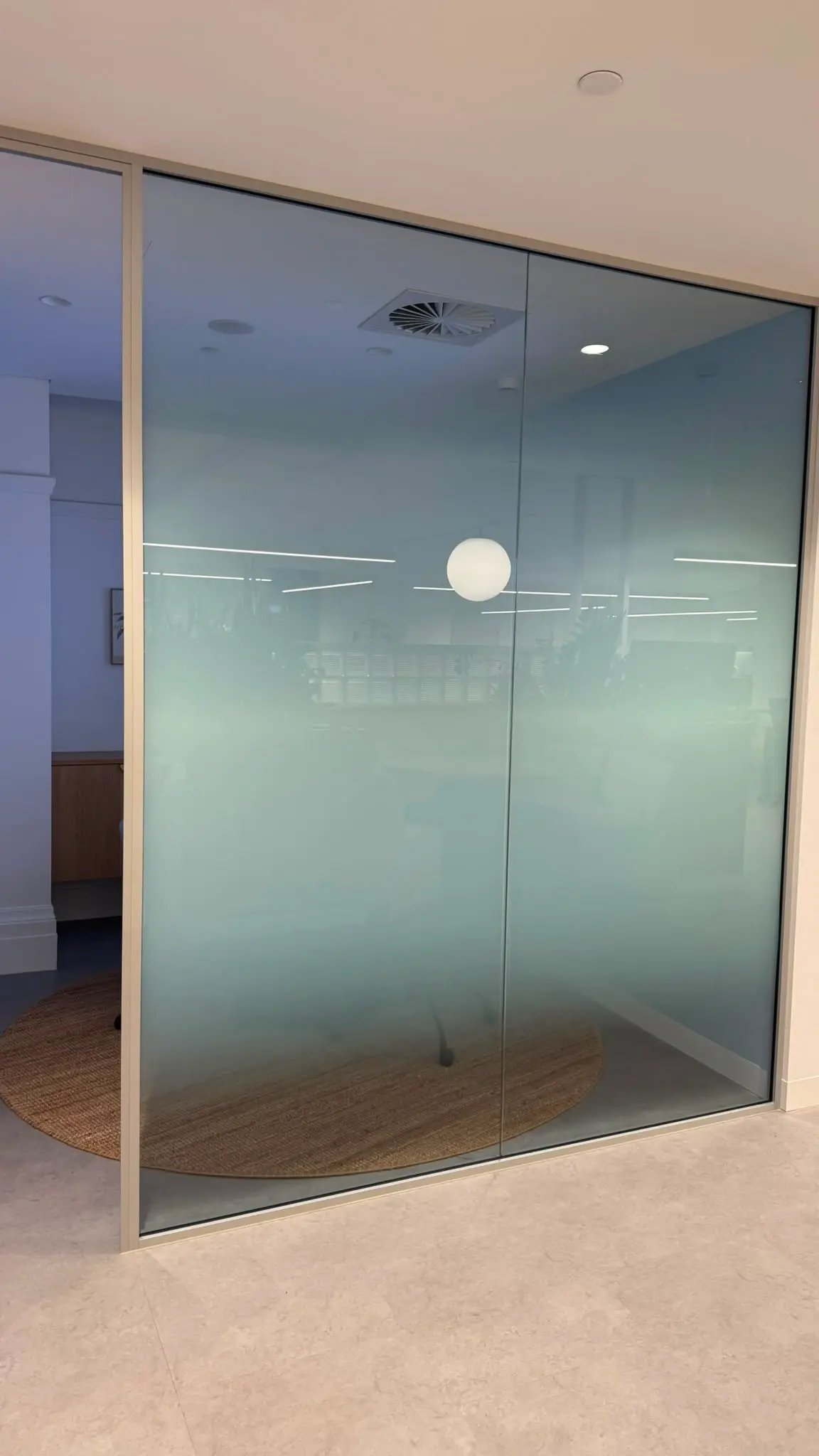 Internal glazed meeting room where the printed gradient is densest across seated height and fades to clear glass near the ceiling
