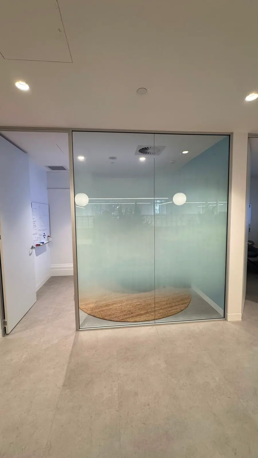 The same glazed meeting room with printed gradient film installed, screening the table and chairs while the top of the glass stays clear