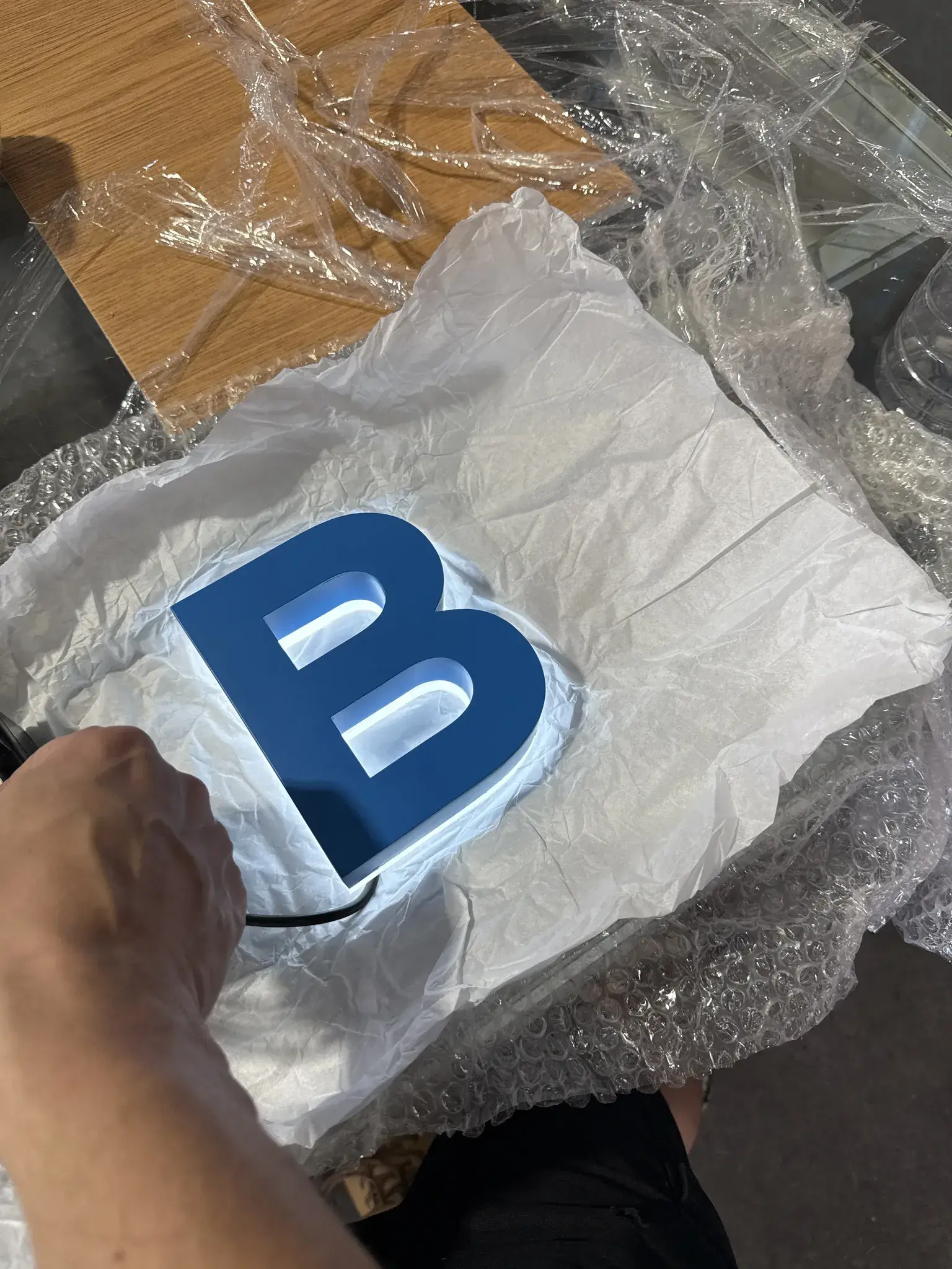 Blue BYRONS letter component illuminated during a workshop bench test before installation