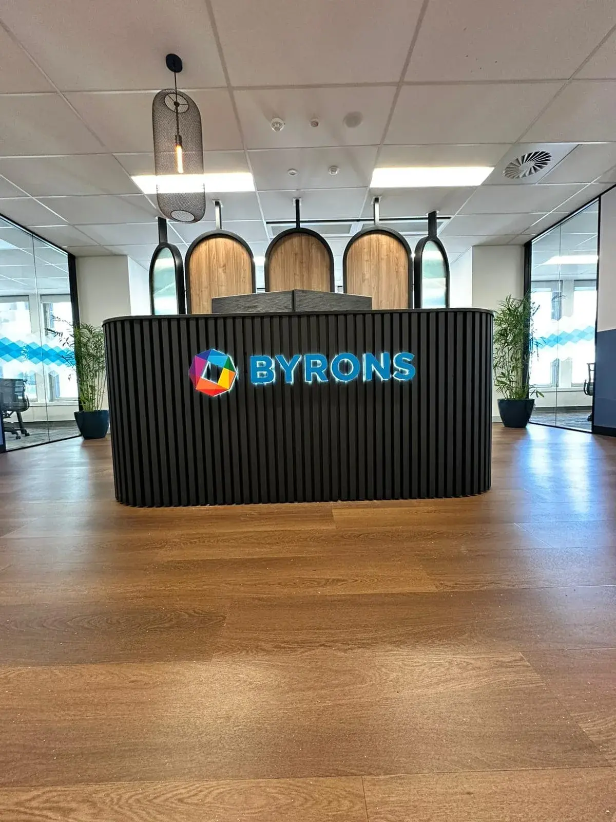 Completed illuminated BYRONS logo and dimensional lettering on a black ribbed reception counter in Sydney CBD