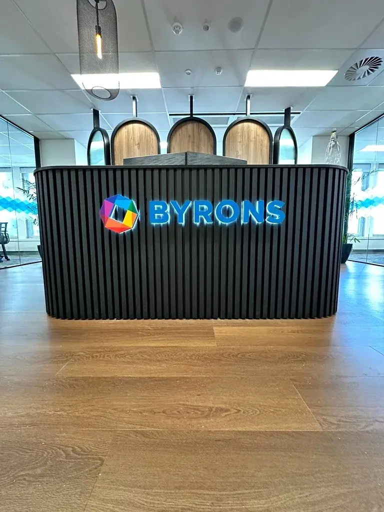 Front view of the completed BYRONS illuminated reception sign with the colour emblem and blue dimensional wordmark