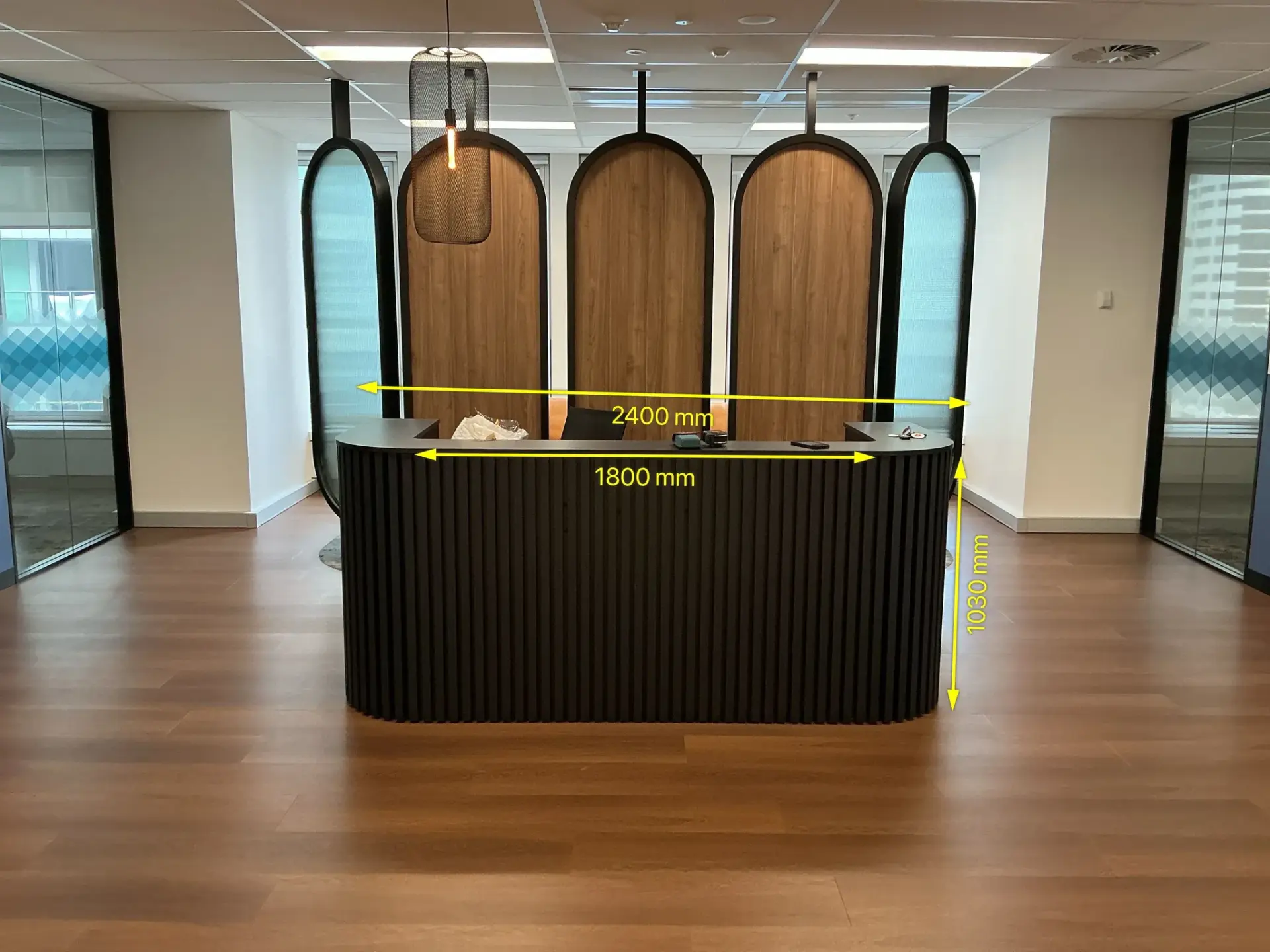 Annotated site-survey photograph of the black ribbed BYRONS reception counter with the available widths and height marked