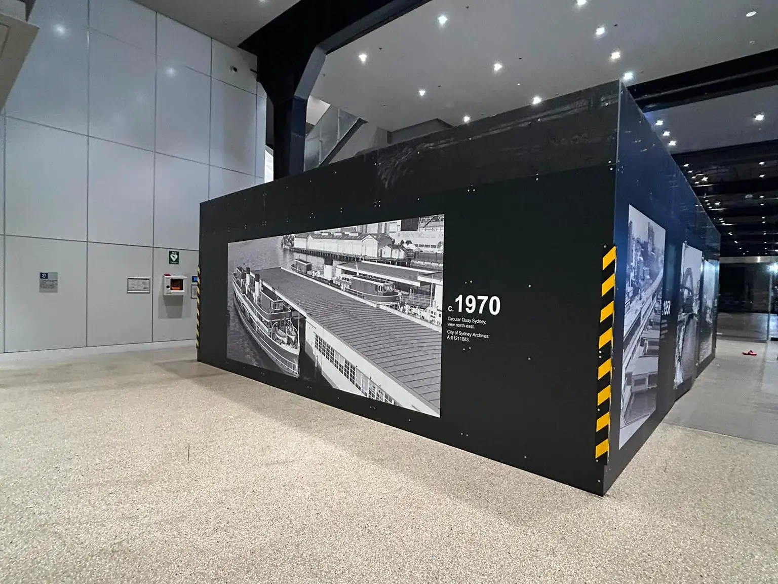 Interior hoarding turning a corner of the terminal, printed the full height of the run with a captioned 1970 view of Circular Quay