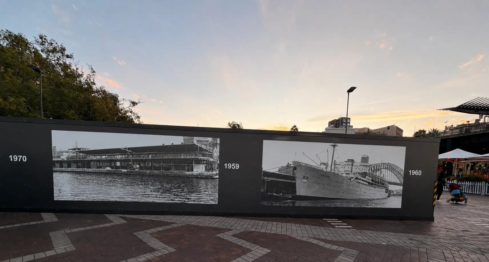 Long run of external hoarding at Circular Quay printed with archival harbour photographs dated 1959, 1960 and 1970