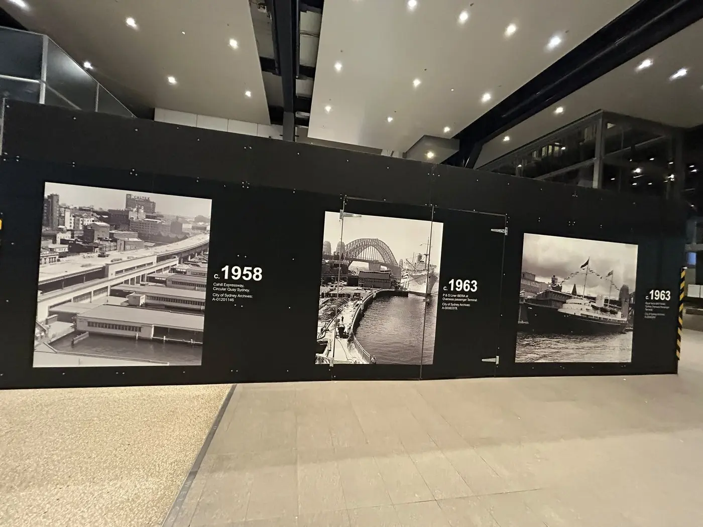 Interior hoarding run inside the terminal printed with captioned archival photographs dated 1958 and 1963