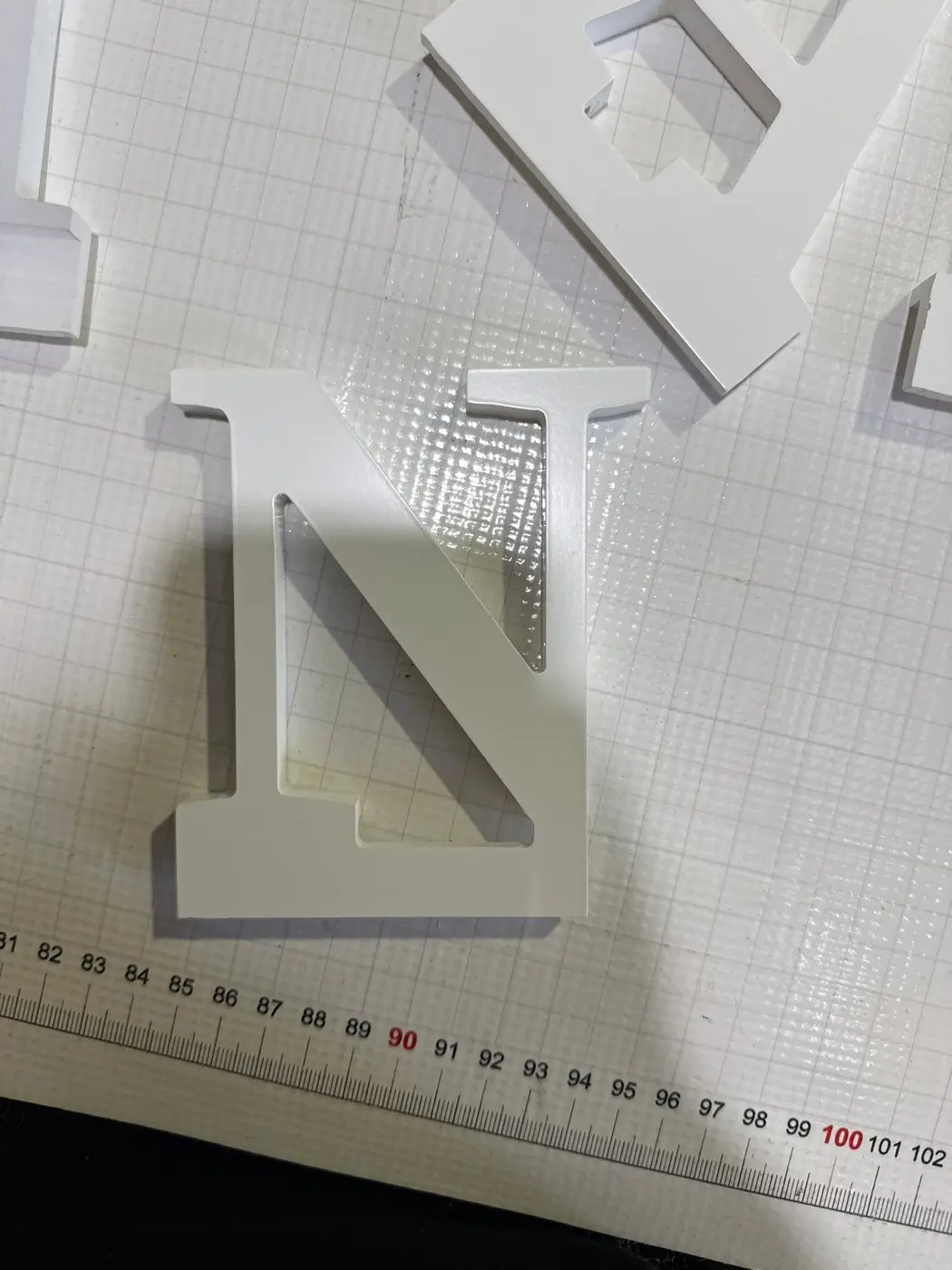 White acrylic letters laid out on a gridded template, part of the interchangeable seasonal menu lettering sets