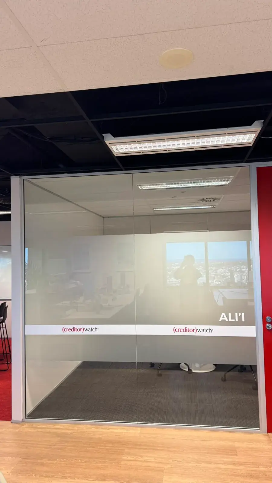 The Ali'i meeting room with a plain frosted privacy band and CreditorWatch room branding on floor-to-ceiling glass