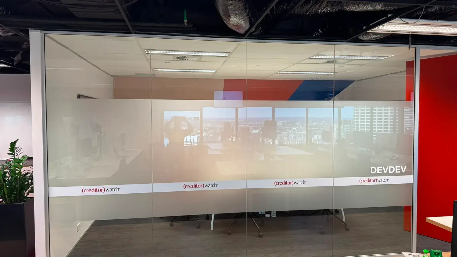 Printed frosted privacy film with a full-width image and CreditorWatch branding on the Devdev meeting-room glass in a Sydney CBD office