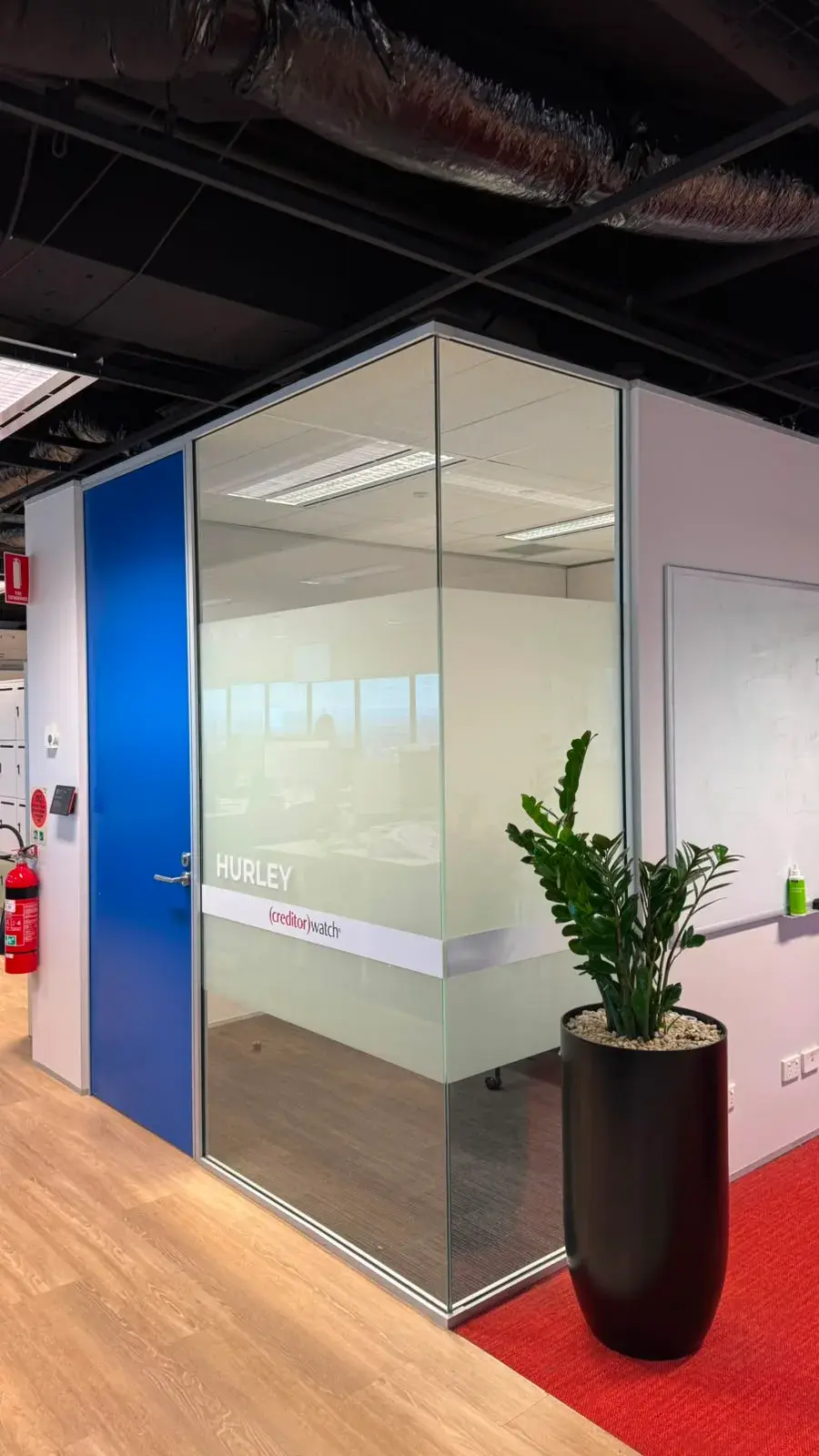 The Hurley meeting room showing a plain frosted privacy band and room name on glass beside a blue office door
