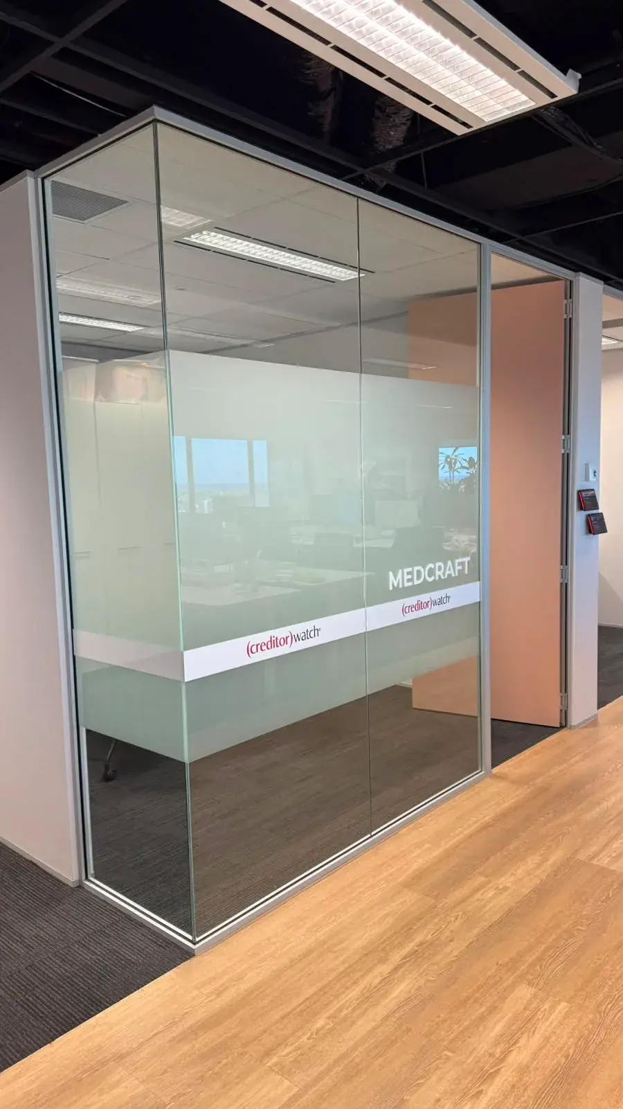 The Medcraft corner meeting room with a printed frost band and CreditorWatch branding wrapping two glass walls