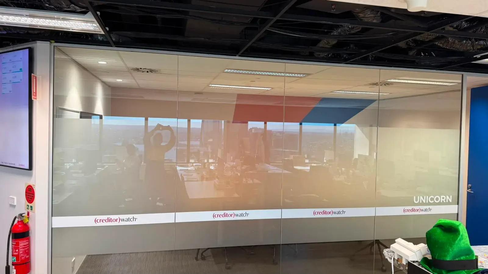 The Unicorn room's four-panel glass wall with a printed frosted band, room name and CreditorWatch identity