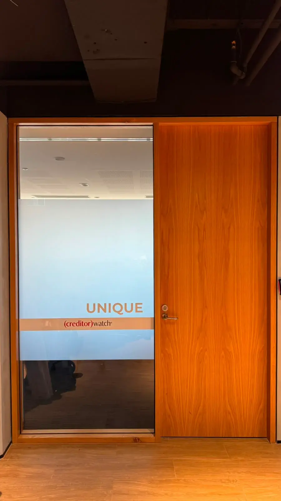 The Unique room glass with a warm coloured frost band and matching room name beside a timber office door