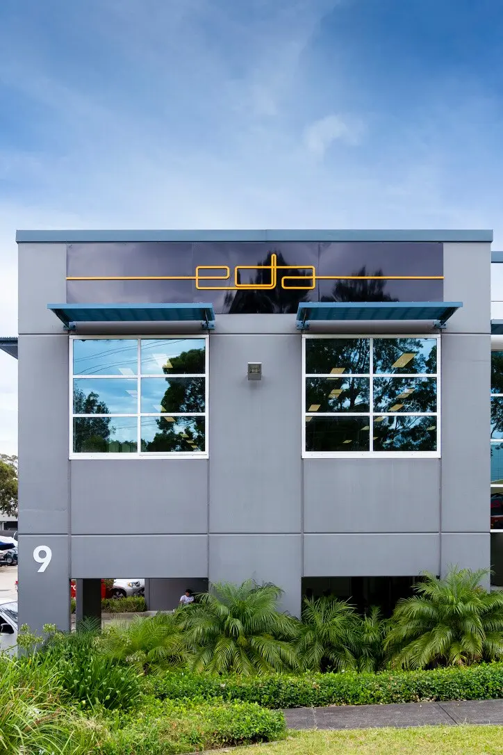 Full Sydney building elevation with the completed yellow EDA logo across gloss-black ACM panels