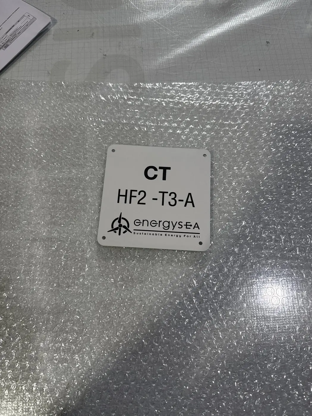 Small square current transformer equipment label with the EnergySEA logo, wrapped for delivery