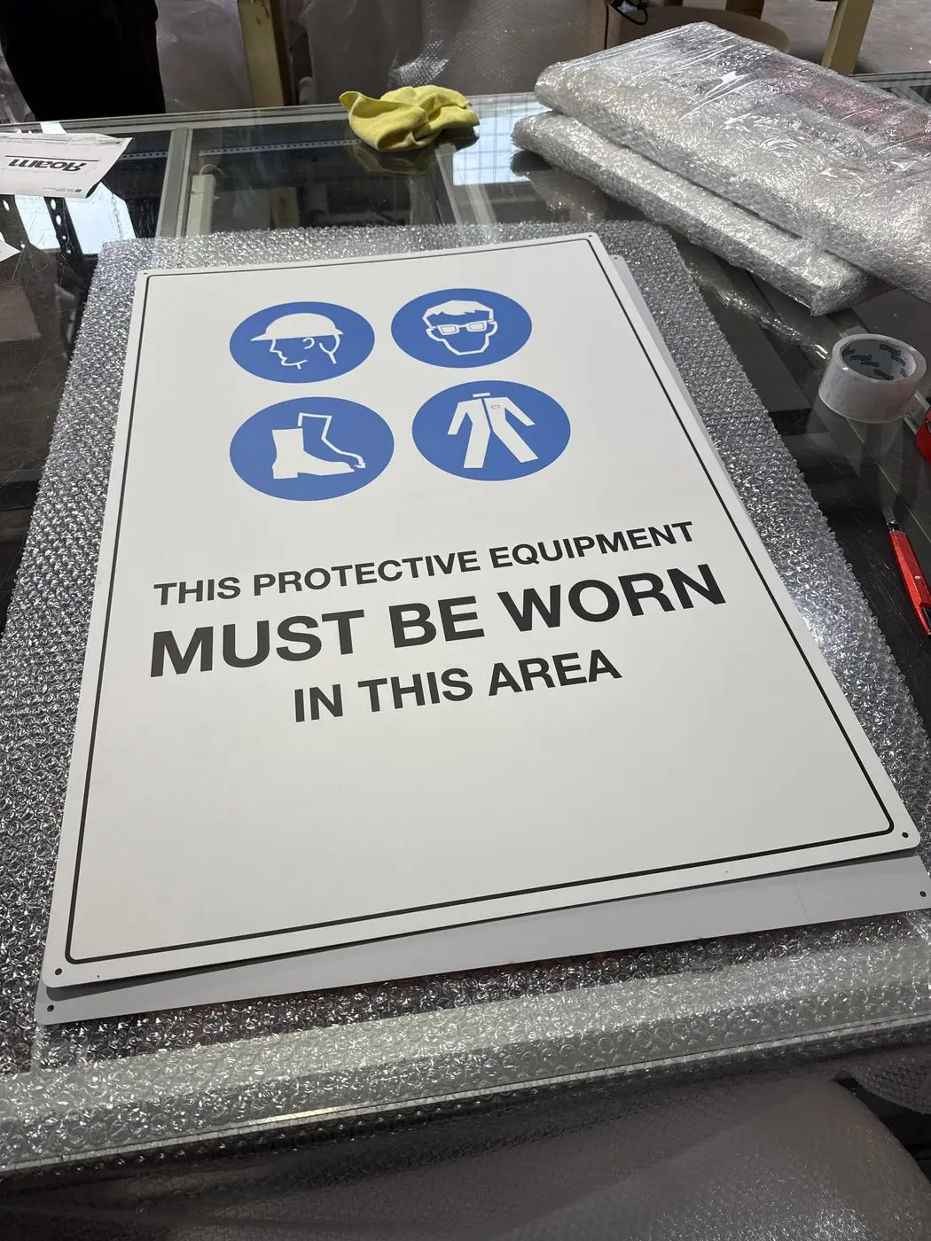 Blue and white protective equipment must be worn sign with four PPE pictograms on the bench
