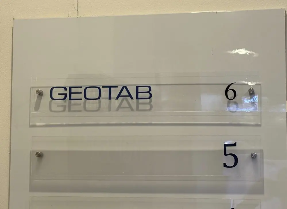 Close view of the clear acrylic directory strip showing the reverse-printed lettering standing off the wall on barrel fixings
