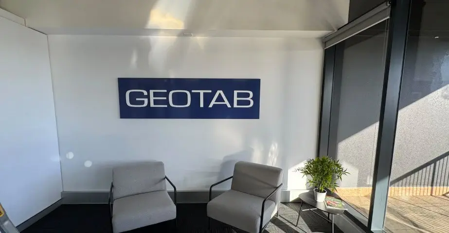 Geotab wall sign installed on a white reception wall beside seating and a window in the Pyrmont office