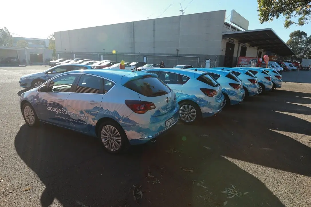 Row of wrapped Google Street View vehicles parked side by side outside the workshop in morning sun