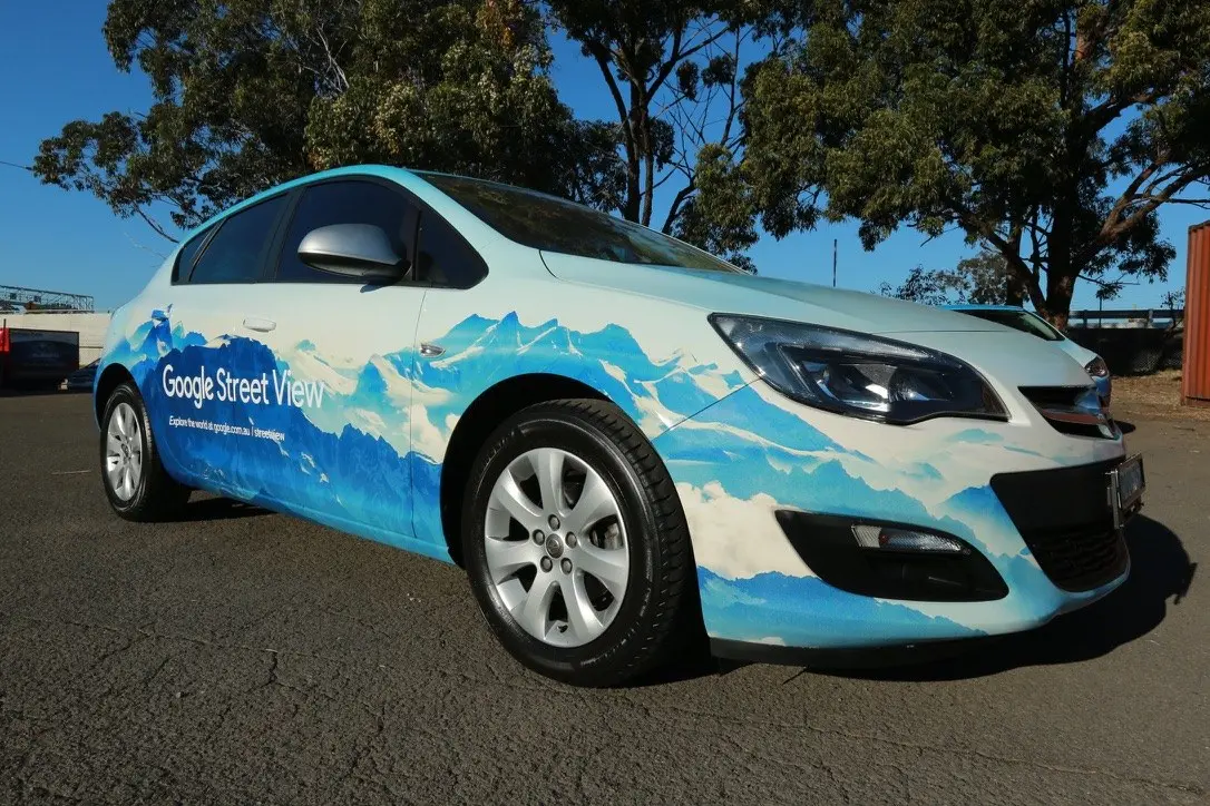 Front three-quarter view of a single wrapped vehicle showing the mountain artwork flowing across the bonnet and doors