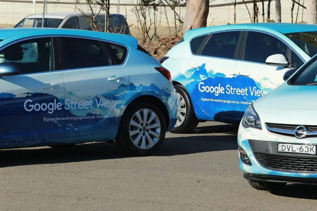 Two wrapped vehicles nose to tail showing the Google Street View logo and Explore the world tagline on the doors