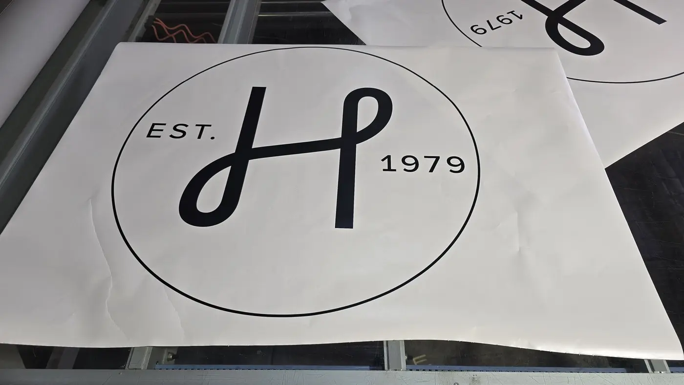 The HALI H monogram inside a fine circle printed on white media on a flatbed printer during the workshop build