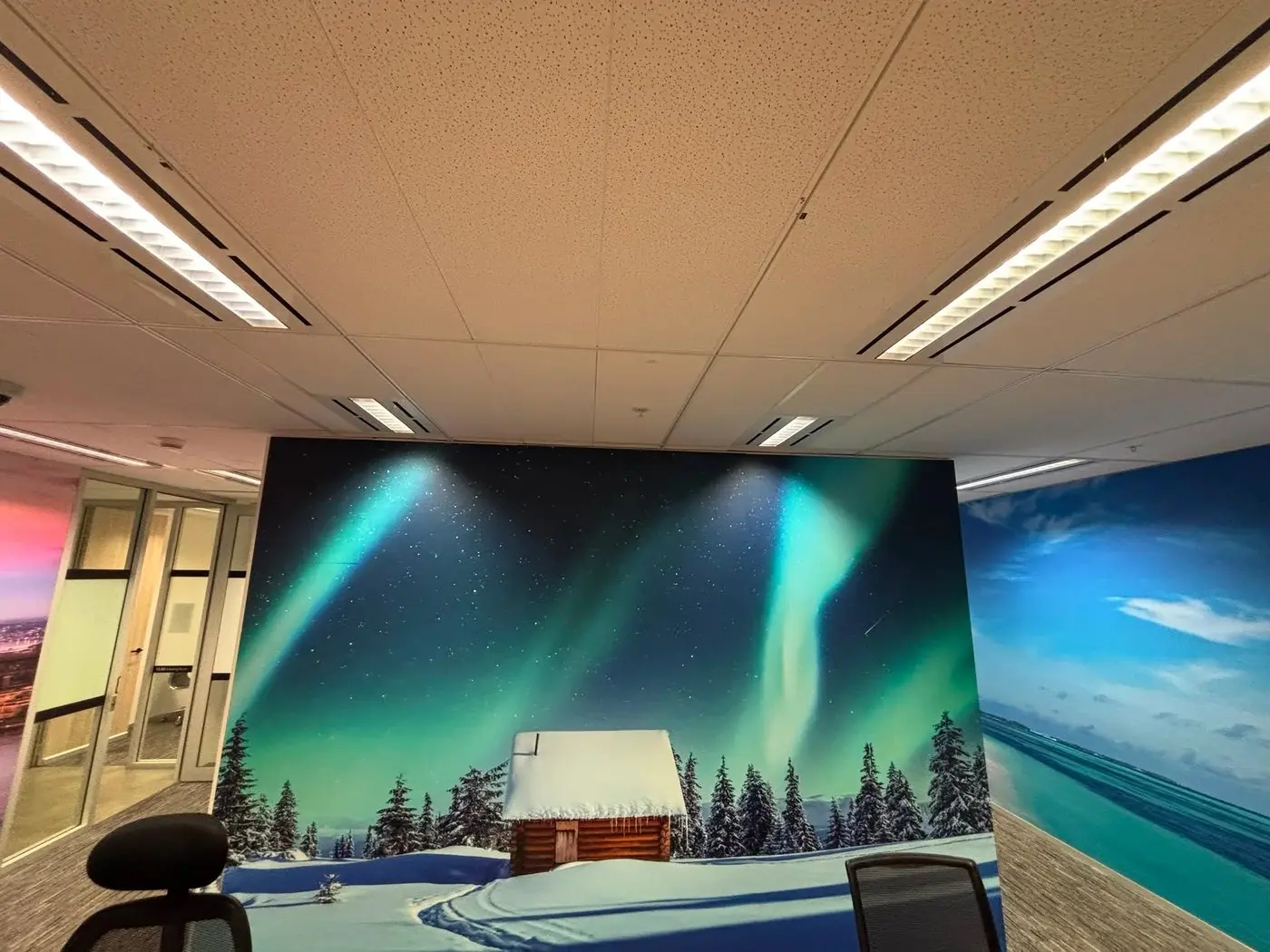 Office view showing an aurora mural on one wall and a tropical beach mural continuing on the next