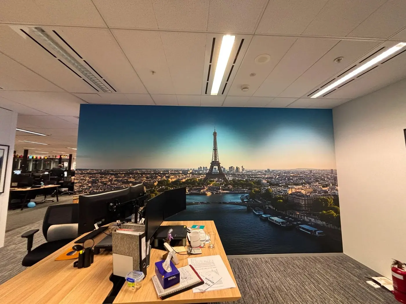 Paris skyline mural with the Eiffel Tower installed along the wall beside office workstations