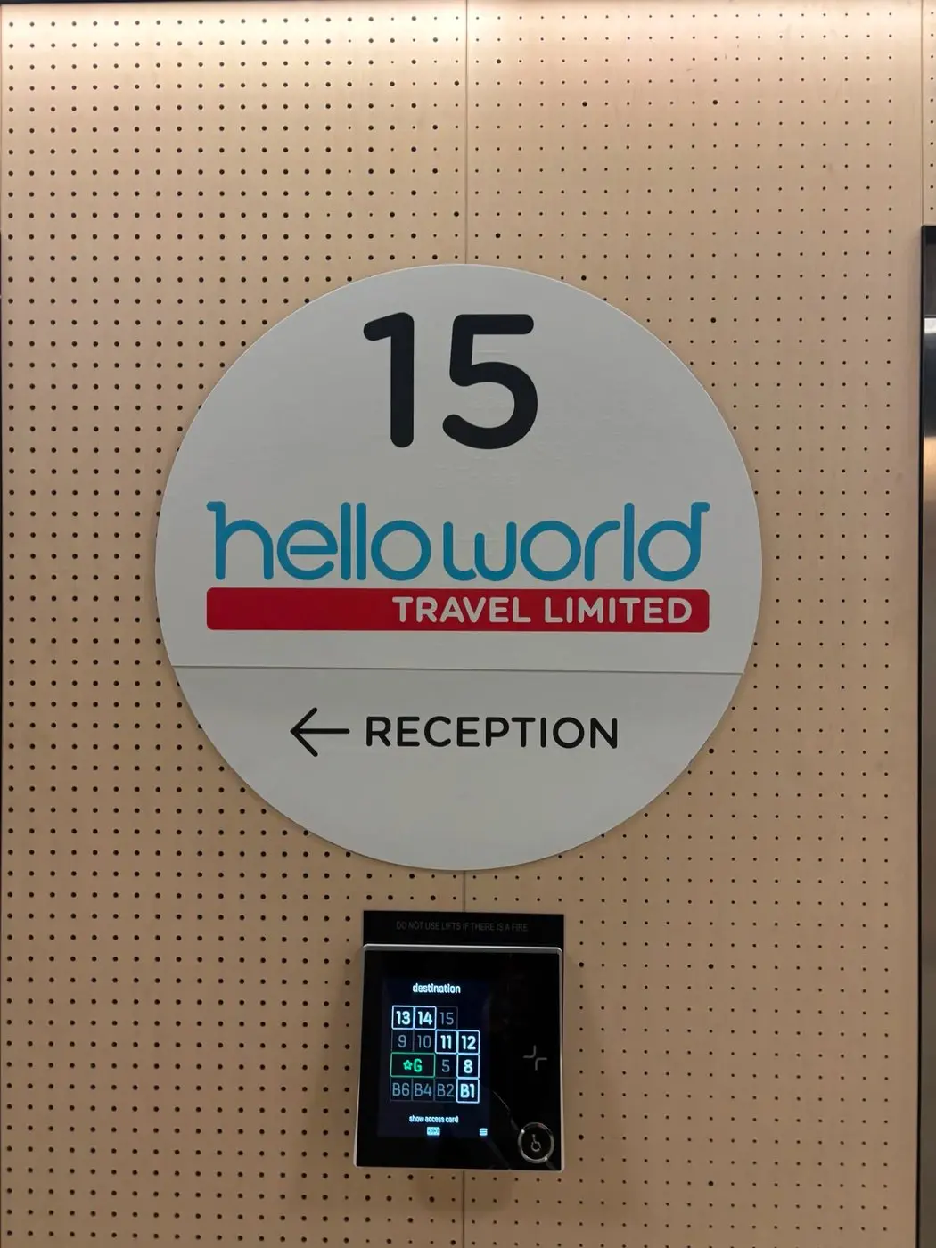 Round Helloworld Travel Limited reception roundel with level number and arrow mounted in the lift lobby