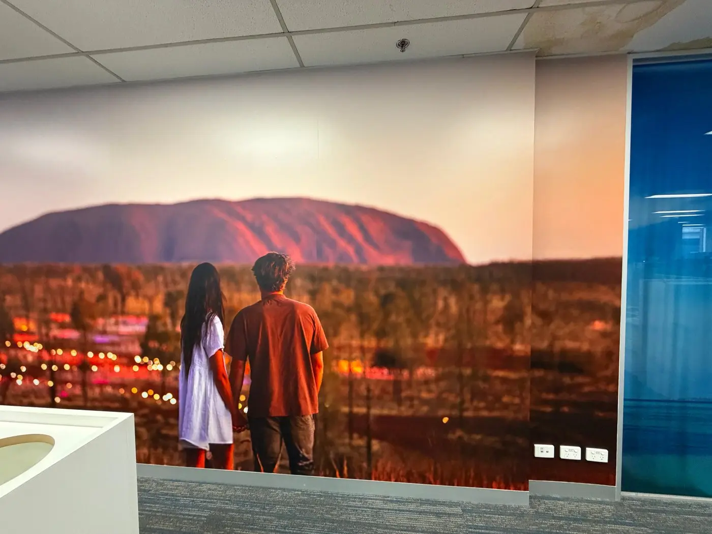 Wall mural of two people watching Uluru at sunset, installed full height in the office