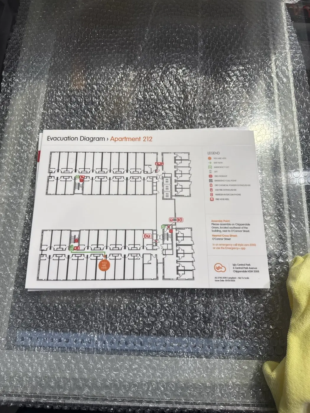Close view of a printed apartment evacuation diagram panel with floor plan, legend and assembly point details