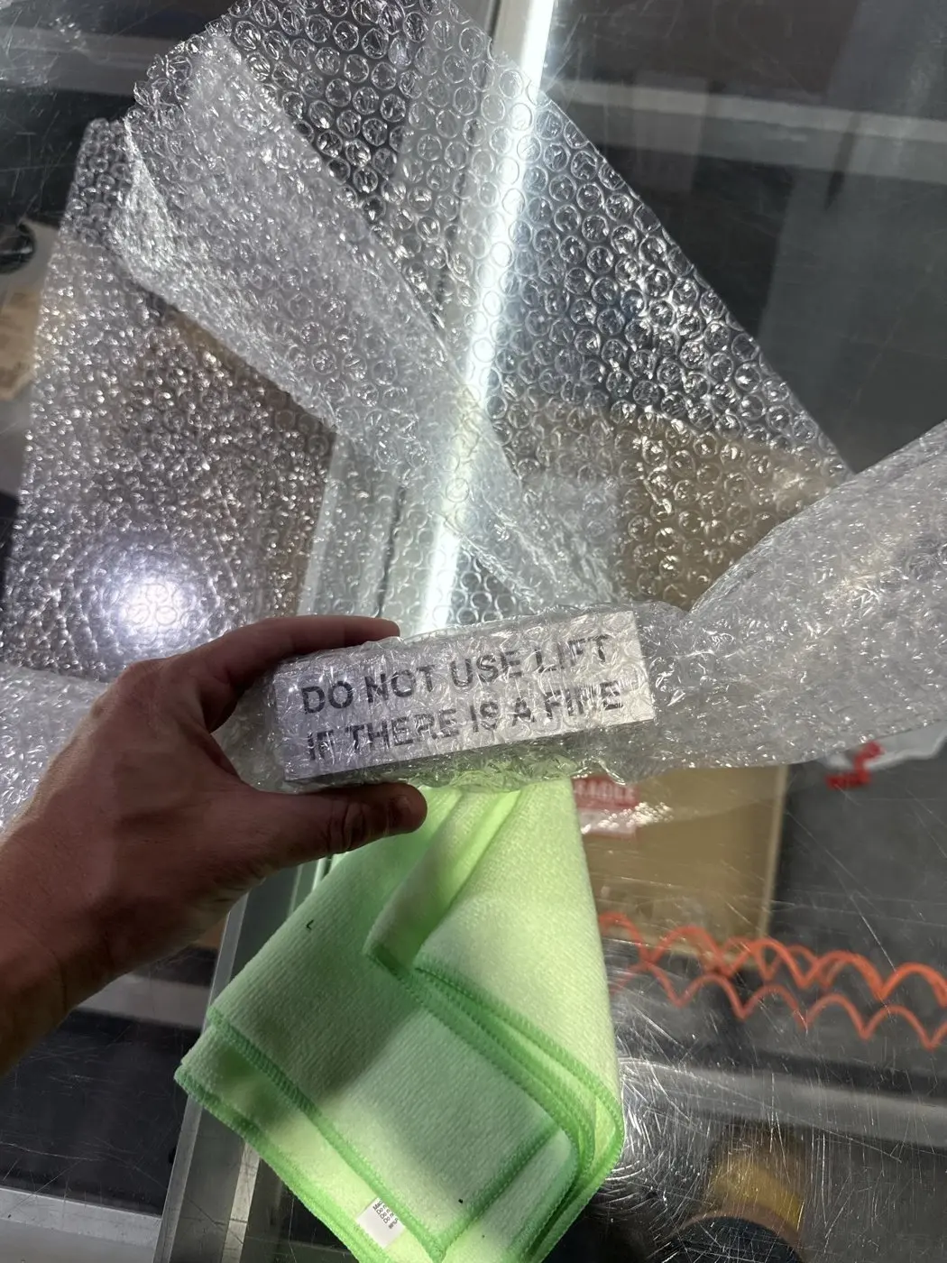 A silver Do Not Use Lift sign held in hand during unwrapping, showing the panel finish