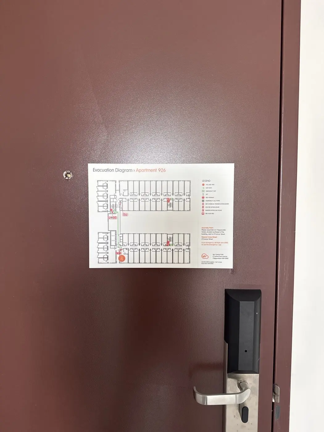 Apartment-specific evacuation diagram panel installed on a dark apartment door at Iglu Central Park in Chippendale