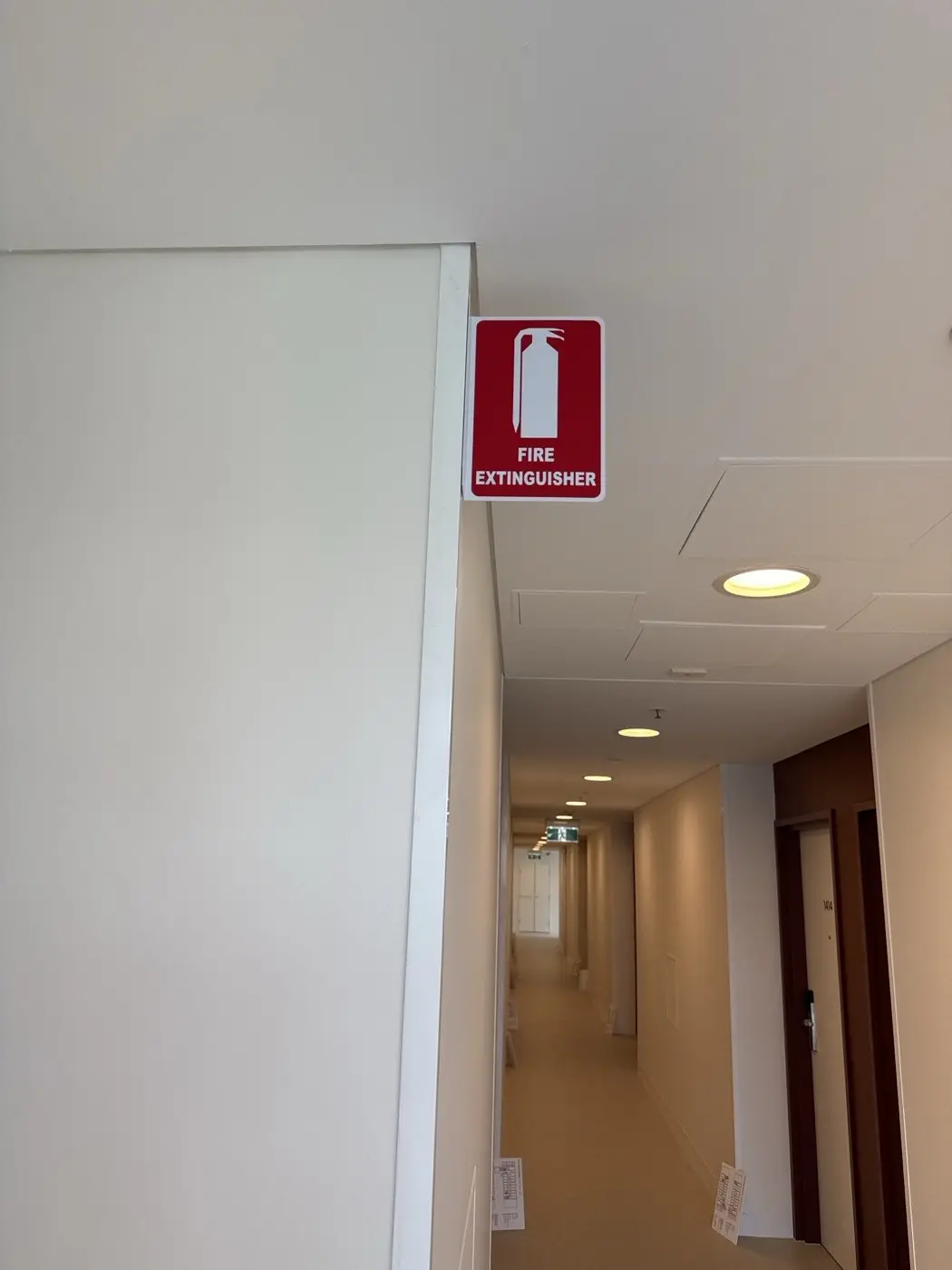 Red fire extinguisher location sign projecting from a corridor wall inside the building