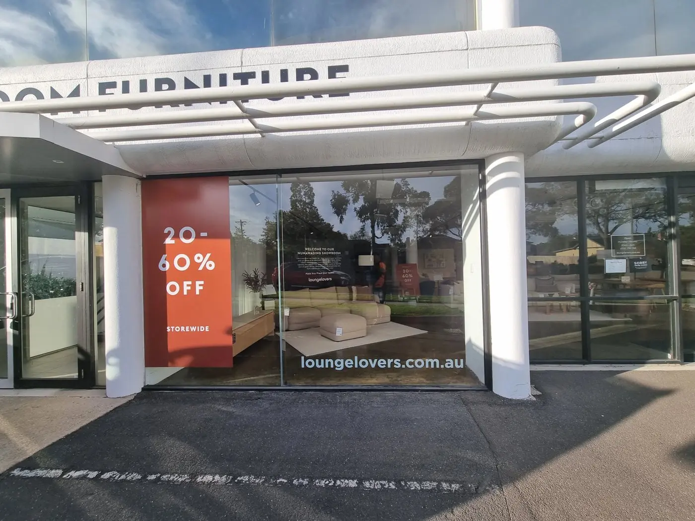 Furniture showroom with arched entry carrying Birthday Sale panels in its display windows