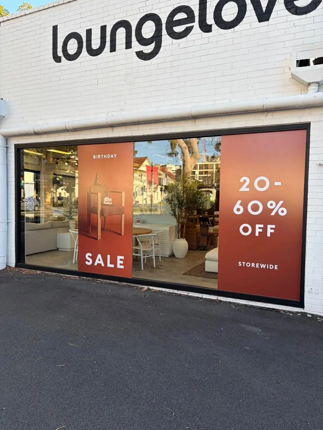 Open corner showroom entry with Birthday Sale panels on the surrounding glass